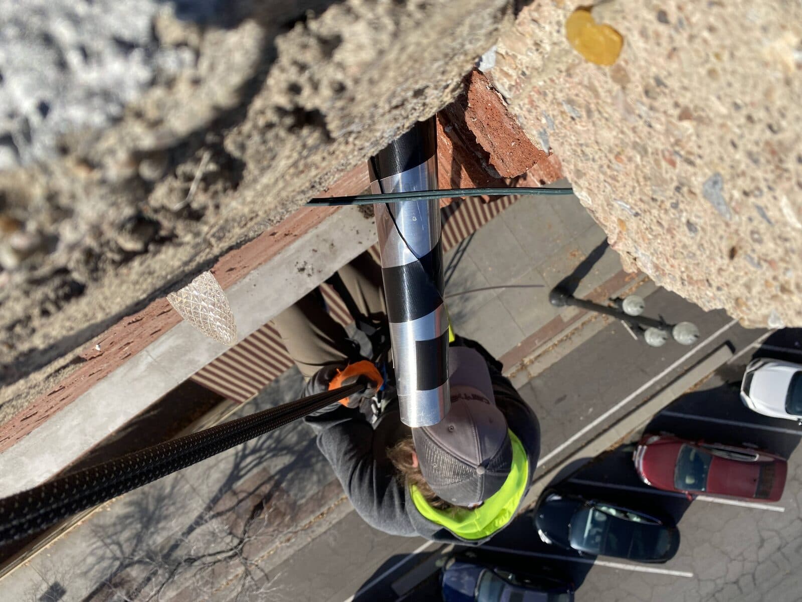 Rope-access technician installing a one-way exclusion tube on a multi-story facade